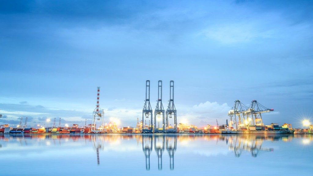 landscape photo of port, boats, cranes and shipping materials