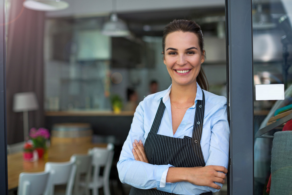 business owner crossing her arms while smiling in front of the establishment