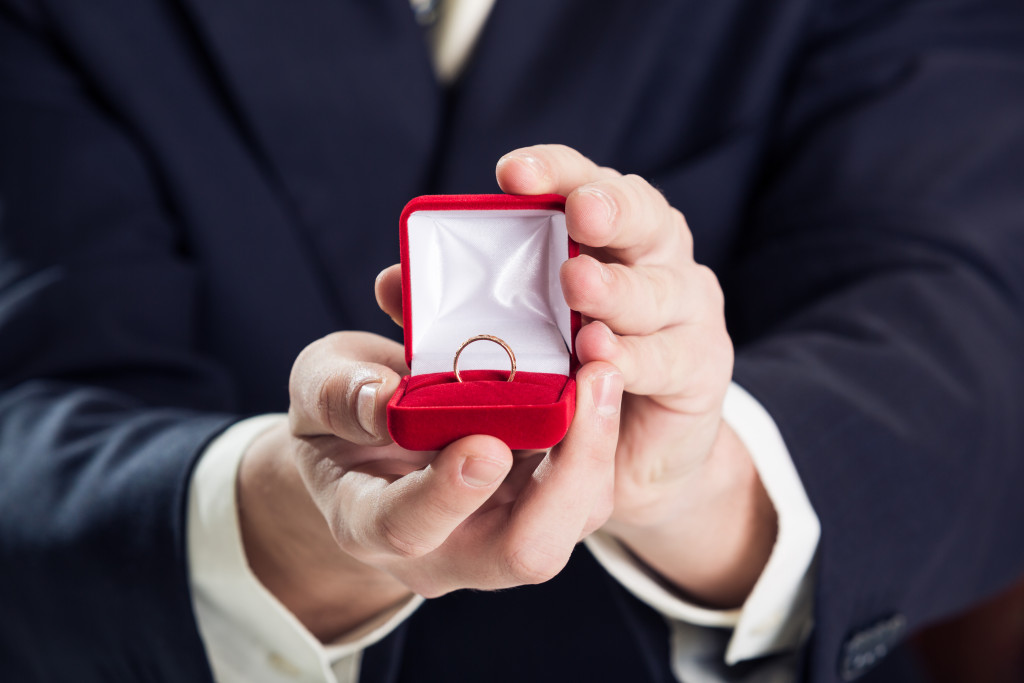 a close up of a man holding an red velvet engagement ring box