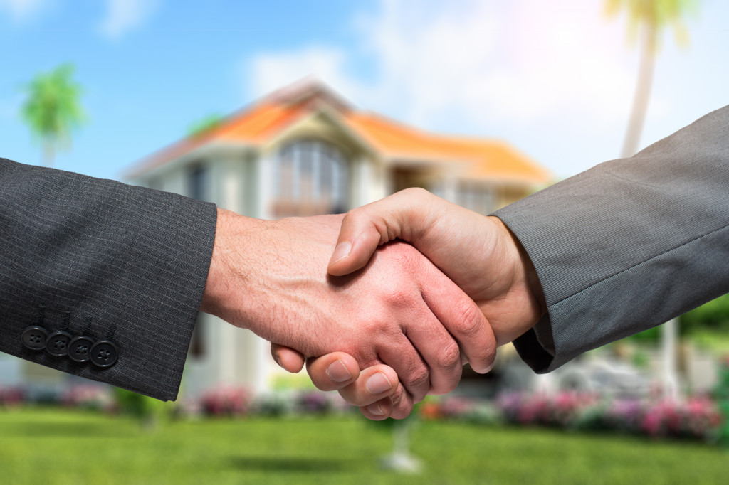 a female hand shaking hands with a male hand representing a real estate transaction