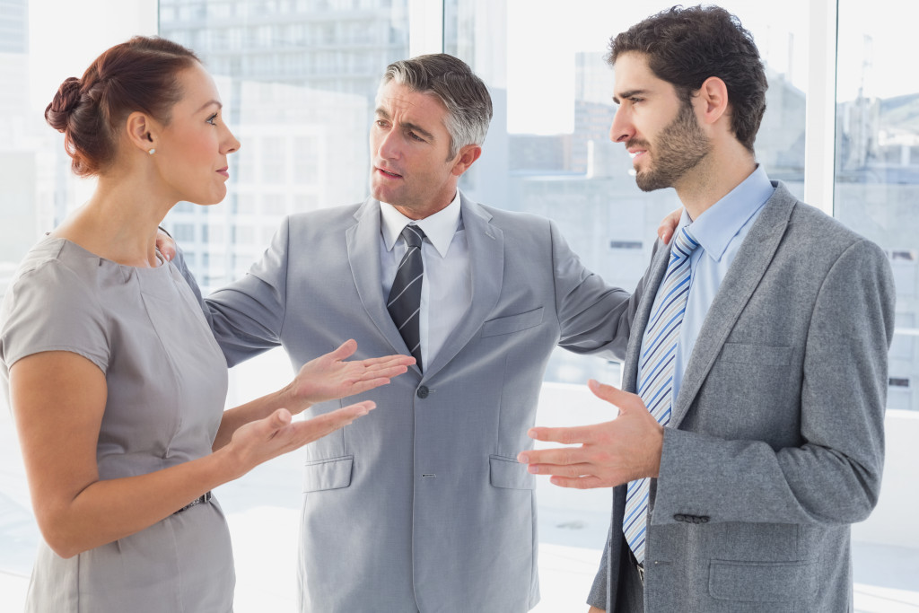 A man trying to resolve conflict between two co-workers in the office