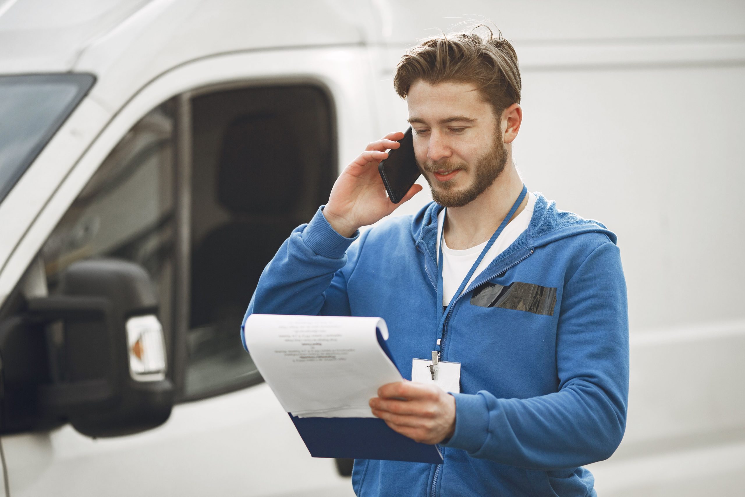 man talking on a phone, with a white truck in the background